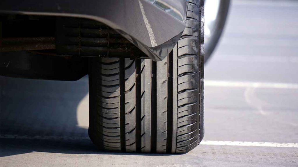 A close-up view of a car tire, showcasing its tread pattern and rubber texture in detail.